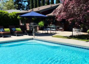 a swimming pool with a table and an umbrella at DunMovin’ Oregon in Grants Pass