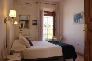 a bedroom with a white bed and a window at Hotel La Zubia , Granada in La Zubia