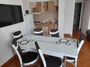 a white dining room table with chairs and a television at APARTAMENT BELUX in Eforie Sud