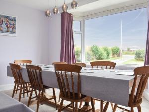ein Esszimmer mit einem Tisch und Stühlen sowie einem großen Fenster in der Unterkunft Delmonte in Langwathby