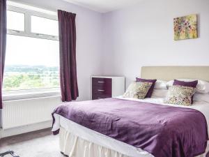 - une chambre avec un lit doté de draps violets et une fenêtre dans l'établissement Delmonte, à Langwathby