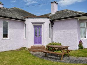 une maison avec une porte violette et une table de pique-nique dans l'établissement Delmonte, à Langwathby