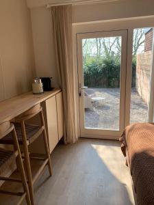 una camera da letto con porta che si apre su un patio di Guest room with terrace at the Wadden Sea a Oosterend
