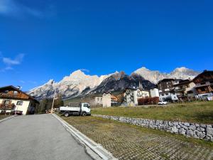 a truck parked on the side of a road with mountains at Hometoday - Appartamento nel cuore di San Vito di Cadore in San Vito di Cadore