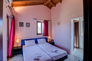 a bedroom with a large bed with red curtains at Athena Villas in Makry Gialos