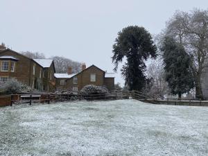 a yard covered in snow in front of a house at Tilly’s stable in Pattishall