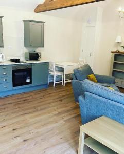 a living room with a blue couch and a kitchen at Tilly’s stable in Pattishall