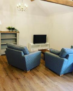 a living room with two blue chairs and a tv at Tilly’s stable in Pattishall