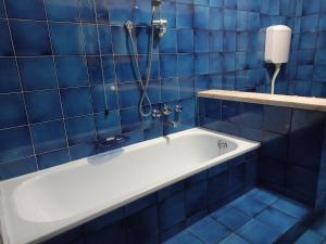 y baño de azulejos azules con bañera y ducha. en B&B Primo Marzo, en Volargne