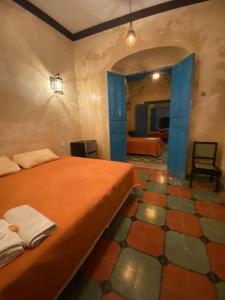 a bedroom with a bed with an orange bedspread and a floor at hotel xucum in Campeche