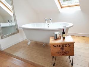 a white bath tub sitting in a bathroom with a bottle of wine at Baltinna West - by Where Stags Roar in Newtonmore