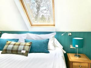 Un dormitorio con una cama con paredes azules y una ventana en Baltinna West - by Where Stags Roar en Newtonmore