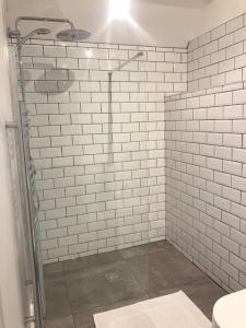 a bathroom with a shower with white tiled walls at John Pallaster Snug in Ubley +7 photos
