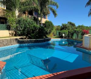 una piscina con agua azul y palmeras en Studio Hina - Cosy, Quiet & Pool, en Papeete