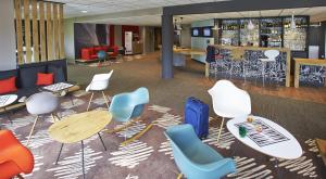a lobby with chairs and tables and a bar at Ibis Auray in Auray