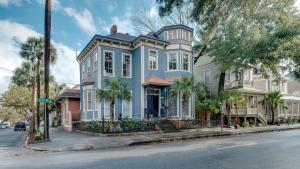 a blue house with palm trees in front of a street at Forsyth Park 2 Bedroom Beauty in Savannah