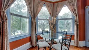 a dining room with a glass table and chairs and windows at Forsyth Park 2 Bedroom Beauty in Savannah