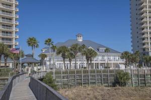 a large white house on the beach with palm trees at Beach Club C1001 Amazing Corner Unit in Gulf Shores