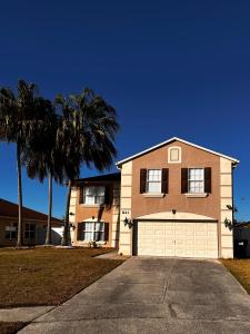 a large house with a garage and palm trees at Nice room near UCF in Orlando