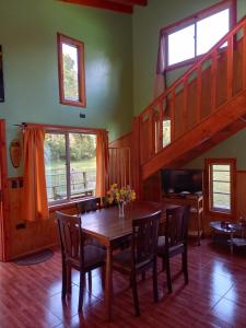 a dining room with a table and chairs and stairs at MagicPlace Neis in Villarrica