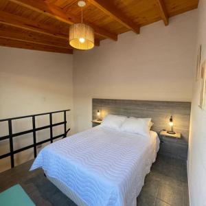 - une chambre avec un lit blanc et un plafond en bois dans l'établissement Hermoso Depto en Comodoro!, à Comodoro Rivadavia