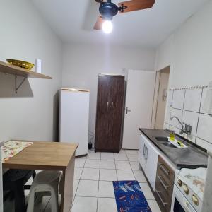 eine Küche mit einer Spüle, einem Kühlschrank und einem Tisch in der Unterkunft Apartamento Praia Coqueiral de Itaparica - Vila Velha in Vila Velha