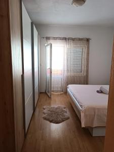 Schlafzimmer mit einem Bett, einem Fenster und einem Teppich in der Unterkunft Apartment "San Marino" in Baška Voda