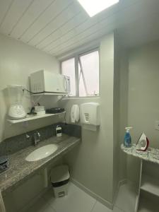 a white bathroom with a sink and a microwave at Veleiro Praia Hotel in Maceió