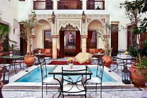 une cour avec des tables et des chaises ainsi qu'une piscine dans l'établissement Riad Al Loune, à Marrakech