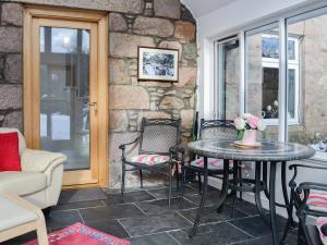 a table and chairs in a room with a stone wall at Craigclunie in Ballater