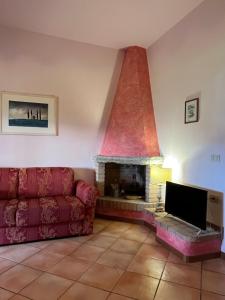 カシャーナ・テルメにあるAgriturismo Le Quercioleのリビングルーム(赤いソファ、暖炉付)