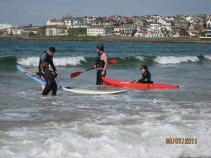 a group of people in the ocean with surfboards at Tranquility Portstewart in Portstewart