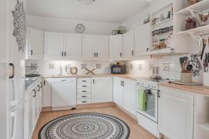 a kitchen with white cabinets and a rug on the floor at Guestly Homes - 4BR City Center Apartment in Piteå