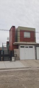 un edificio con dos puertas blancas de garaje en una calle en Departamento América, en Puerto Madryn