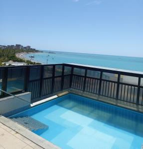 una piscina en un balcón con el océano en el fondo en Apartamento Top a Beira-Mar na Pajuçara - Maceió, en Maceió