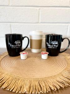 two black coffee mugs sitting on a table with cupcakes at The Postcard Motel in Seligman