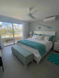 a white bedroom with a bed and a large window at Apartamento frente a Playa in San Pedro de Macorís