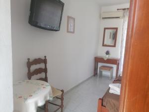 - un salon avec une télévision sur un mur blanc dans l'établissement Kefalos Studios Stamatia, à Kefalos