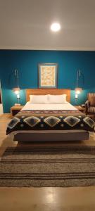 a bedroom with a large bed with a blue wall at Hotel Casa Merced in Cuenca