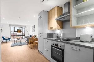a kitchen with white cabinets and a dining room with a table at Pluxa Onyx Luxury 1 bedroom apartment in Birmingham