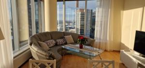 a living room with a couch and a table in front of windows at Luxury Nightlights NELLI Apartment in Tallinn