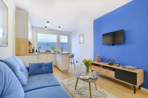 a blue living room with a blue couch and a kitchen at Apartament 4 Pory Roku PRZY PLAŻY Z WIDOKIEM NA MORZE in Gdynia