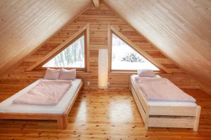 two beds in a wooden room with two windows at Blockhaus am See - Komfort umgeben von Natur! in Nälden