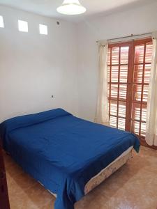 Un dormitorio con una cama azul y una ventana en Casa Alta Gracia - 3 Habitaciones para 6 personas en Alta Gracia