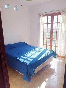 1 dormitorio con cama con sábanas azules y ventana en Casa Alta Gracia - 3 Habitaciones para 6 personas en Alta Gracia