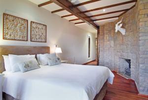 a bedroom with a large bed and a stone fireplace at Lalapanzi Lodge in Somerset West
