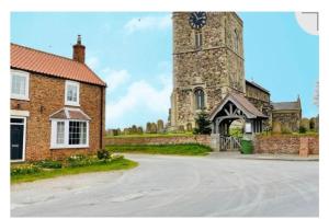 a large brick building with a clock tower at Lychgate view cottage in Aldbrough
