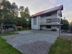 a white house with a balcony on a gravel driveway at Dom w Cygańskim Lesie in Bielsko-Biała