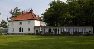 uma grande casa branca com um telhado vermelho em Stegeborg Trädgårdshotell em Stegeborg