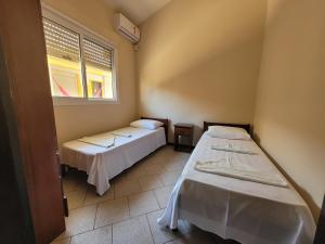 2 camas en una habitación con ventana en Pousada Genoveva - Apto com dois dormitórios, en Laguna
